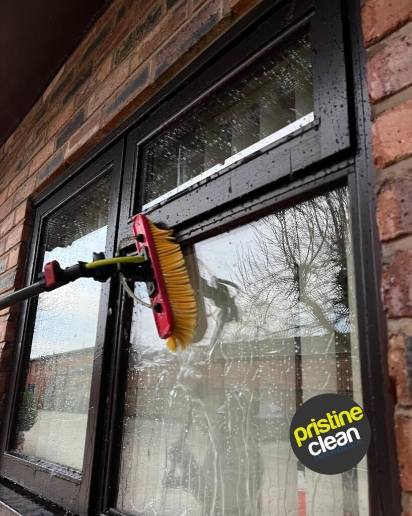 Professional window cleaner in Cheshire cleaning a black framed window using a pure water brush system mid clean
